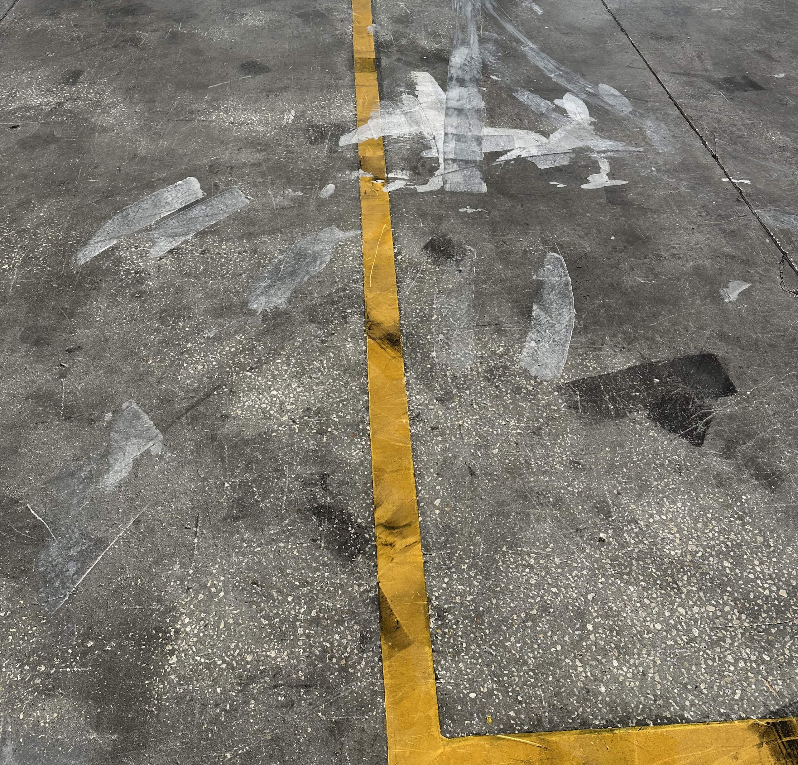 Warehouse concrete marked with pallet scuffs, tire staining and faded line paint before cleaning