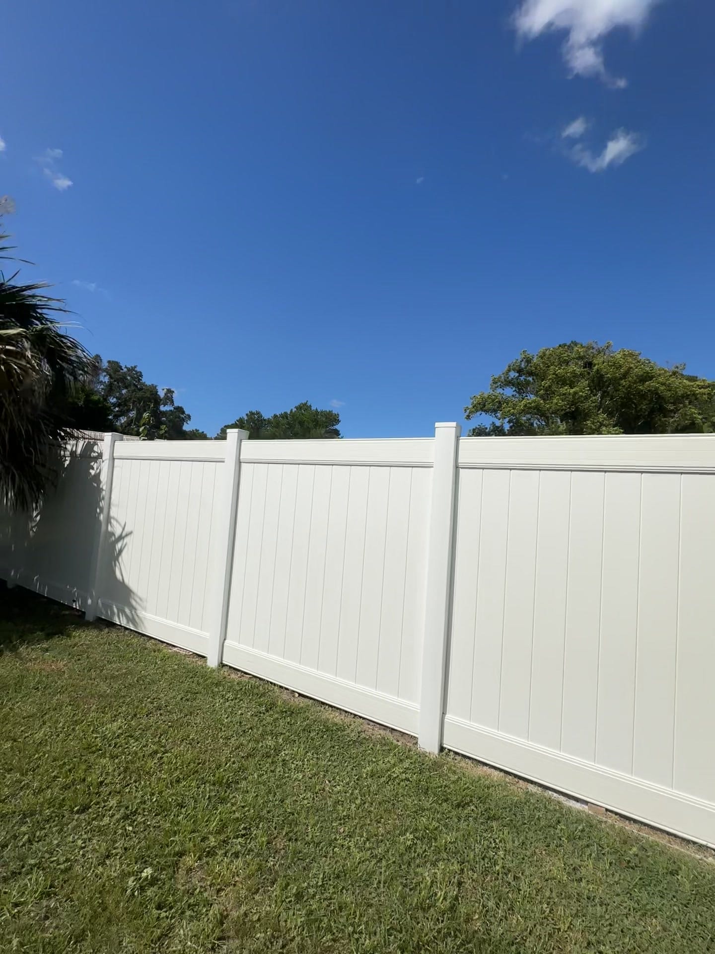 The same Deltona fence after soft washing, clean and bright white against blue sky